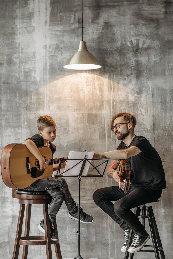 Teacher and young boy in guitar lesson, under modern lighting, indoors.