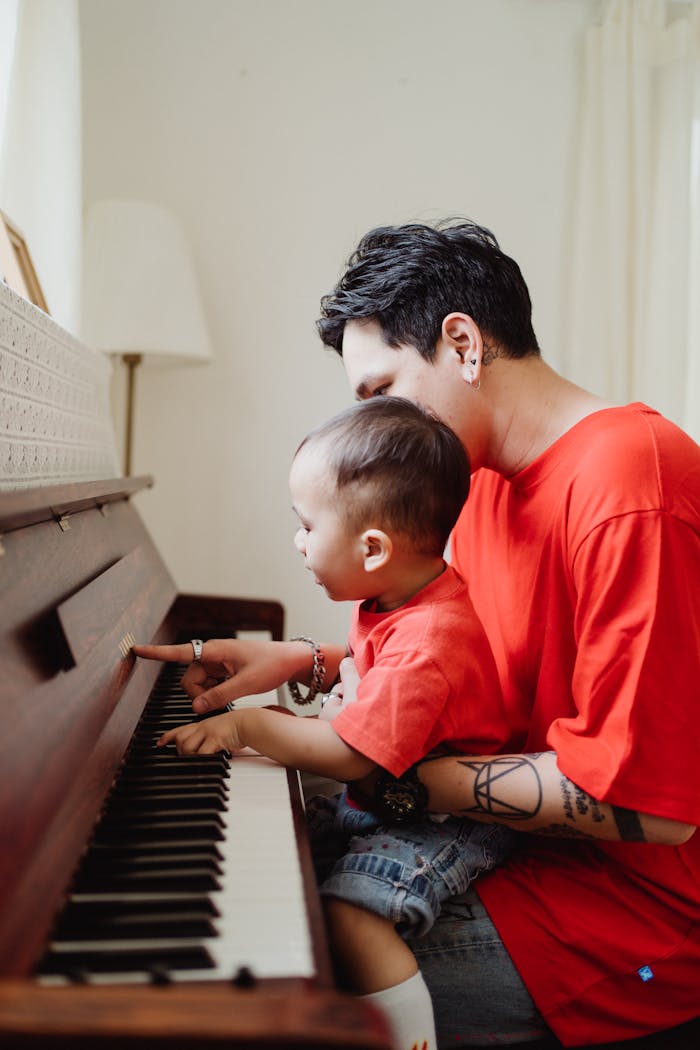 A father teaches his son to play piano, showcasing bonding and musical education.